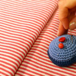 anna * pollack, Nadelkissen mit Hand auf gestreiftem Stoff