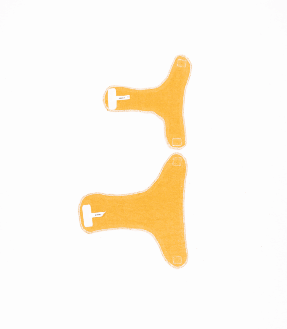 gelbe Puppenwindeln aus Stoff, offen liegend, einmal groß, einmal klein