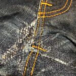 Hosenrepartur Denim, Blue Jeans repariert im Schlitz mit der Nähmaschine