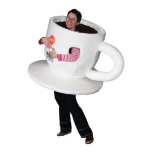 Frau mit einem Kaffeetassenkostüm bzw Maskottchen. Beine, Arme und Kopf schauen heraus, Körper ist in einer weißen Kaffeetasse mit Kaffee Innen.